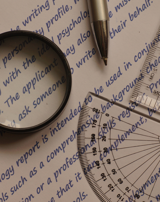 Graphology and handwriting analysis - magnifying glass along with pen, on a piece of paper.